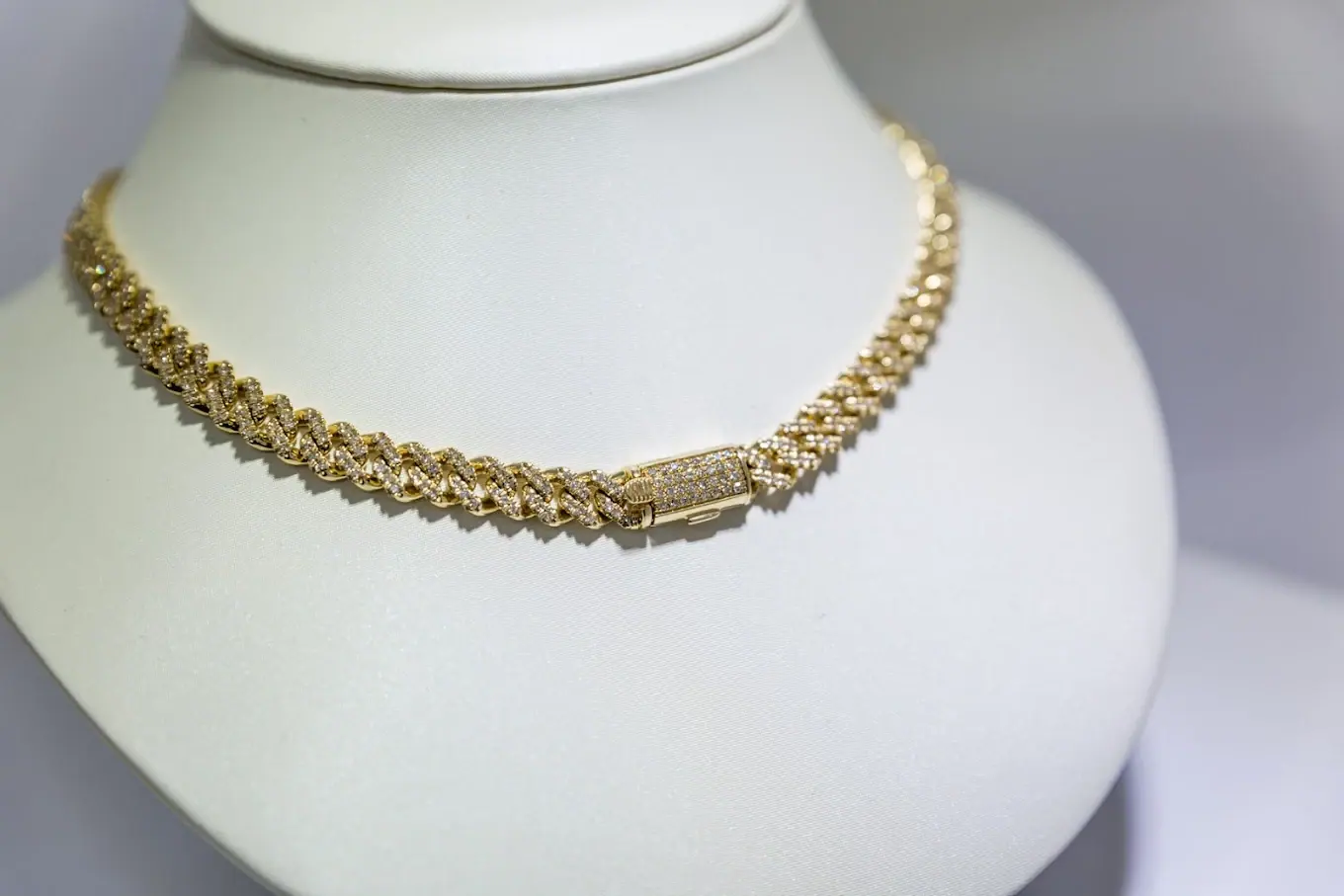 Diamond-set Cuban link chain in yellow gold on a display bust