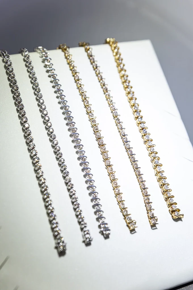 Diamond tennis bracelets in white and yellow gold laid out on a tray