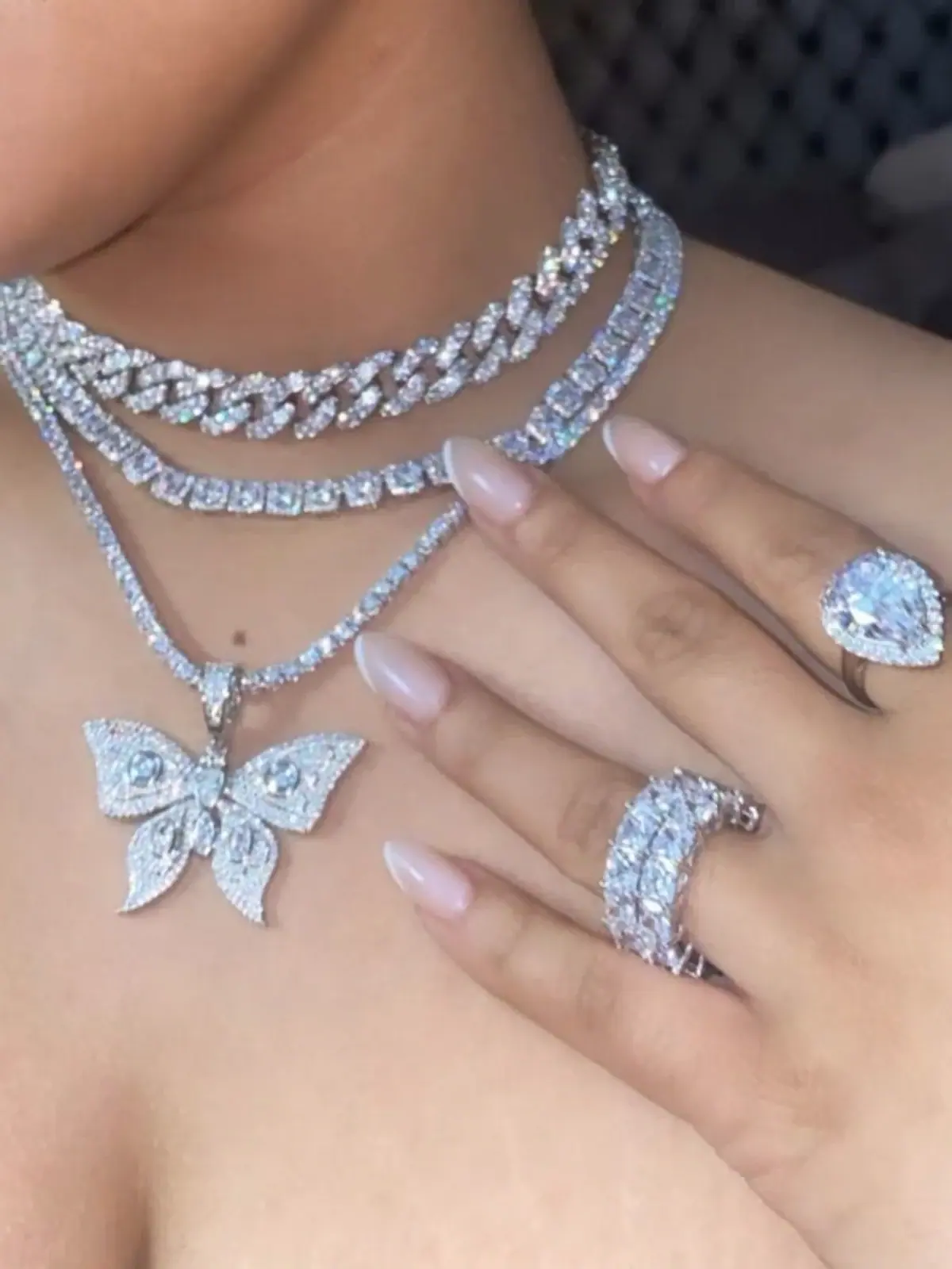 Woman wearing layered diamond chains, a butterfly pendant and diamond rings