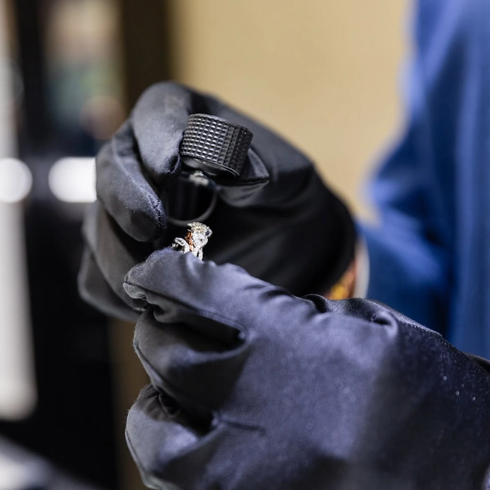 Karats Jewelry specialist in gloves inspecting a diamond ring with a loupe