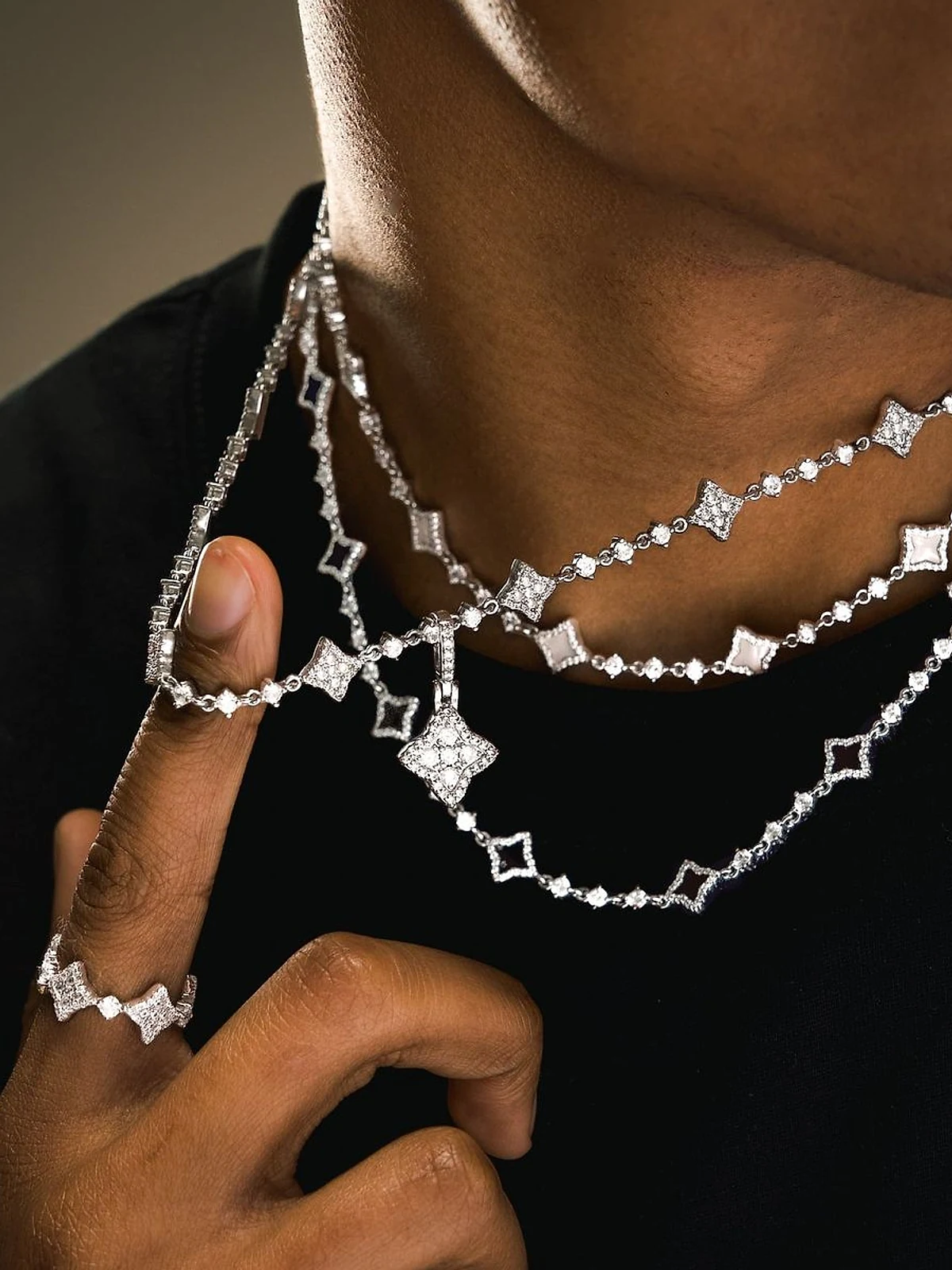 Man wearing layered diamond station necklaces and a diamond ring